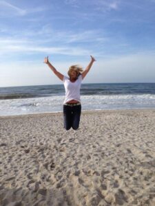 erschoepfung-tcm Frau am Strand macht Freuden-Luftsprung
