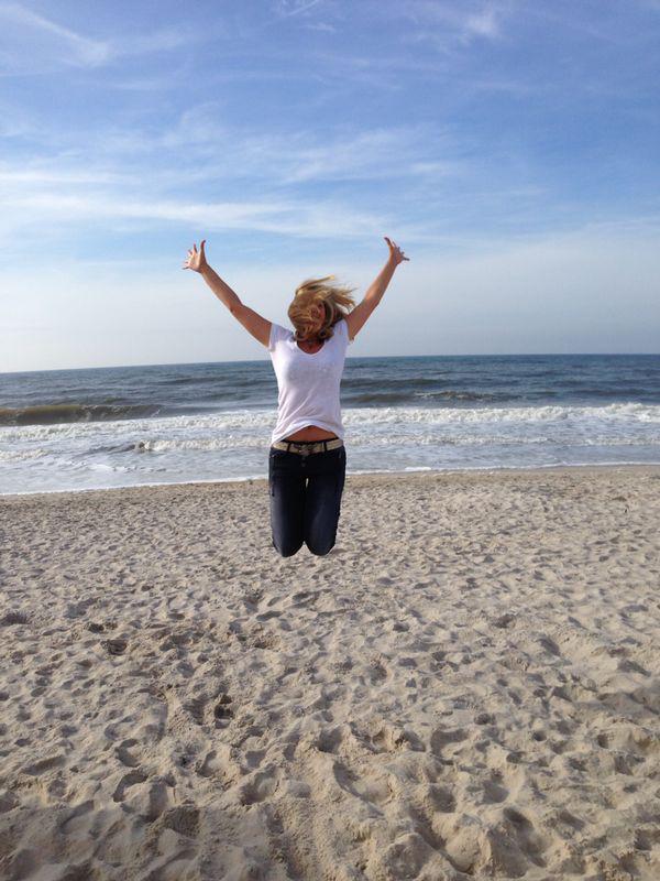 Frau am Strand macht Freuden-Luftsprung