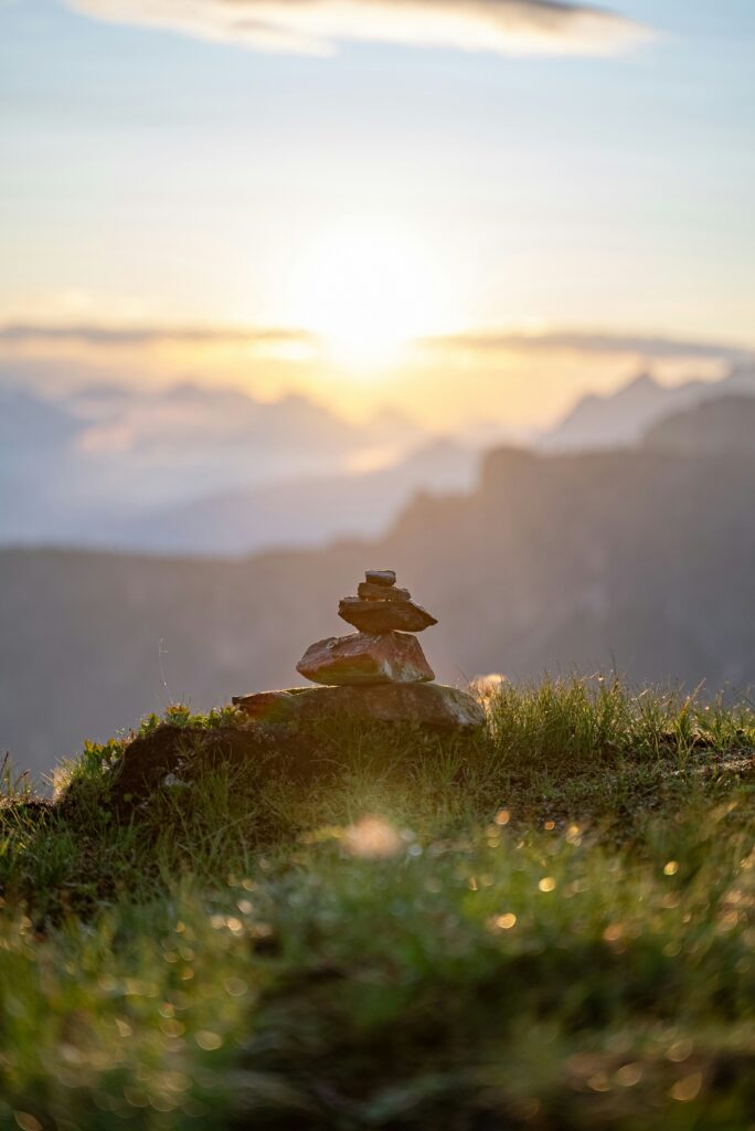 Foto von Nicola Pavan Gestapelte Stein auf einem Hügel mit Sonne im Hintergrund